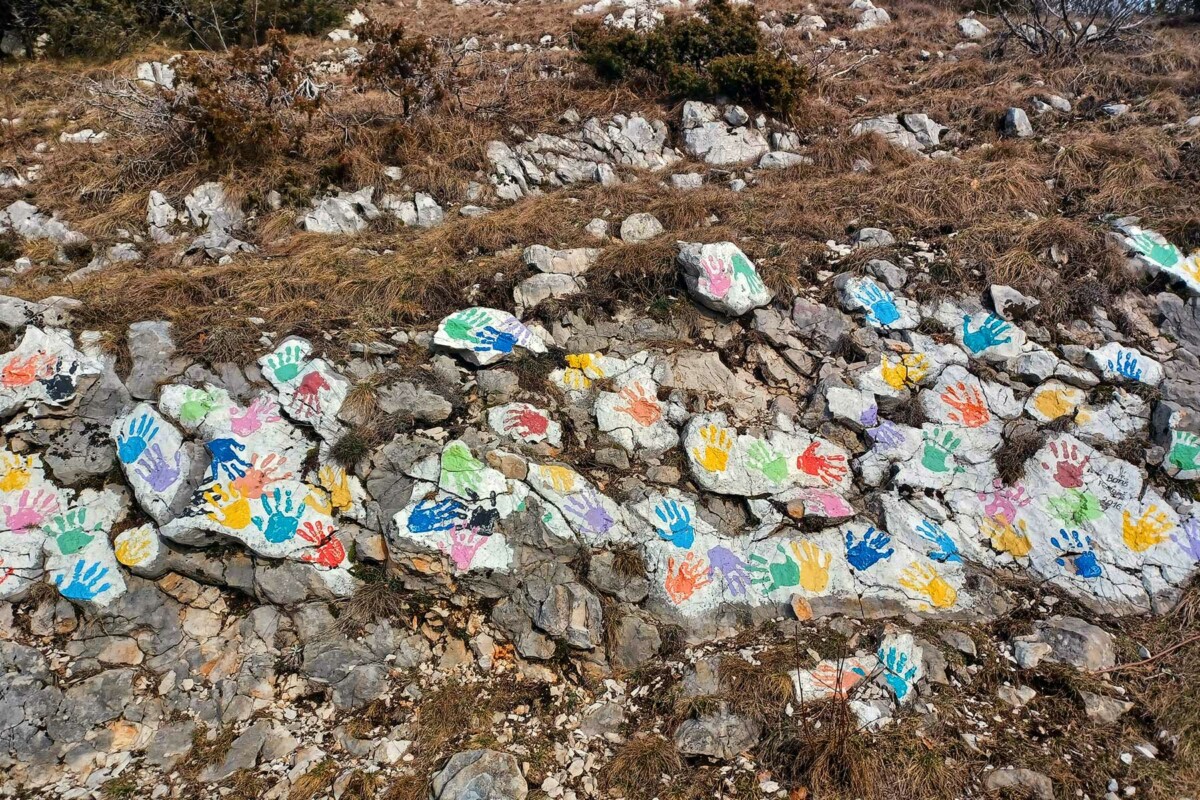 Obojani kamenčići u raznim bojama i oblicima složeni na tlu u prirodi – umjetnička instalacija na Land art stazi na Ćićariji.