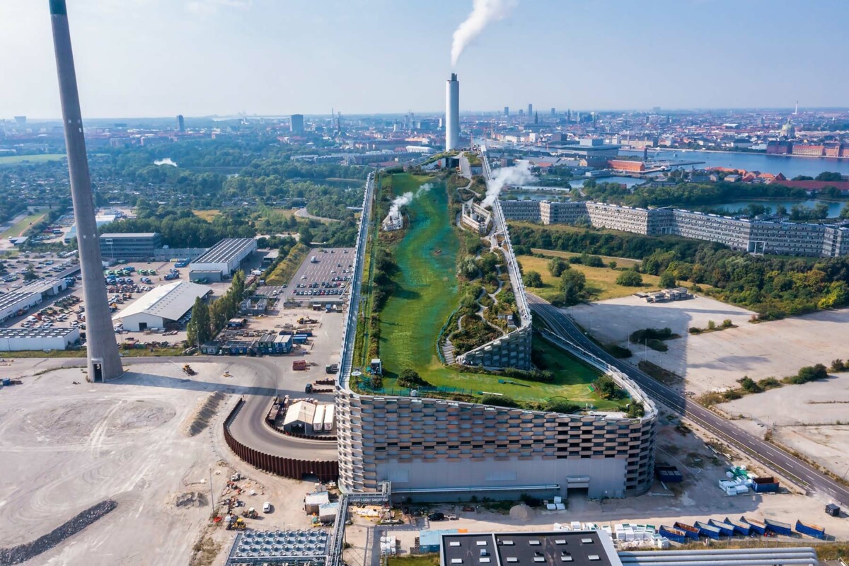 Spalionica otpada Copenhill u Kopenhagenu, s krovištem pretvorenim u zelenu skijašku stazu i pješačku zonu, smještena u urbanom okruženju grada.