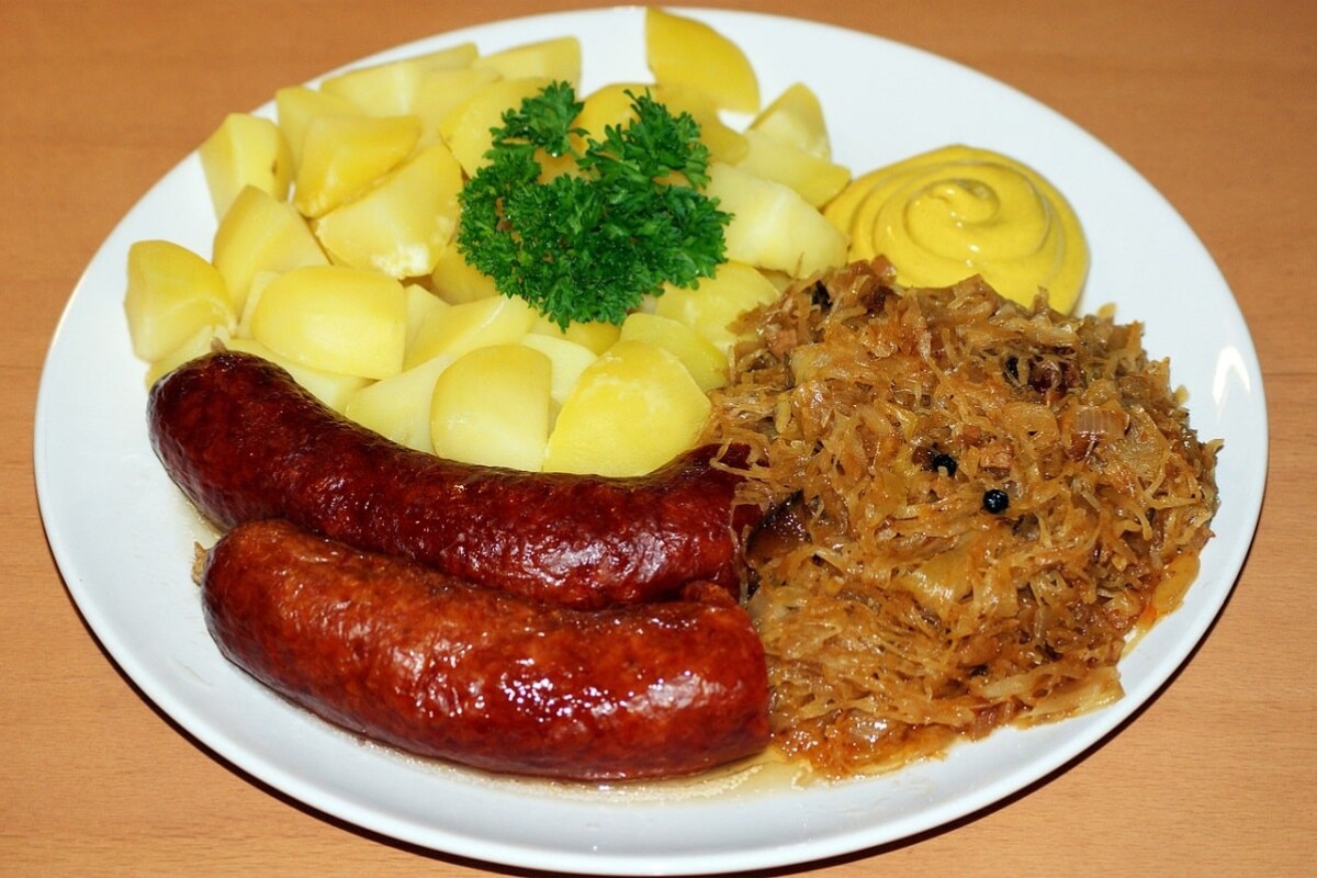 kobasice-kiseli-kupus Tradicionalno jelo s kobasicama, kuhanim krumpirom i kiselim kupusom na tanjuru – klasičan zimski obrok