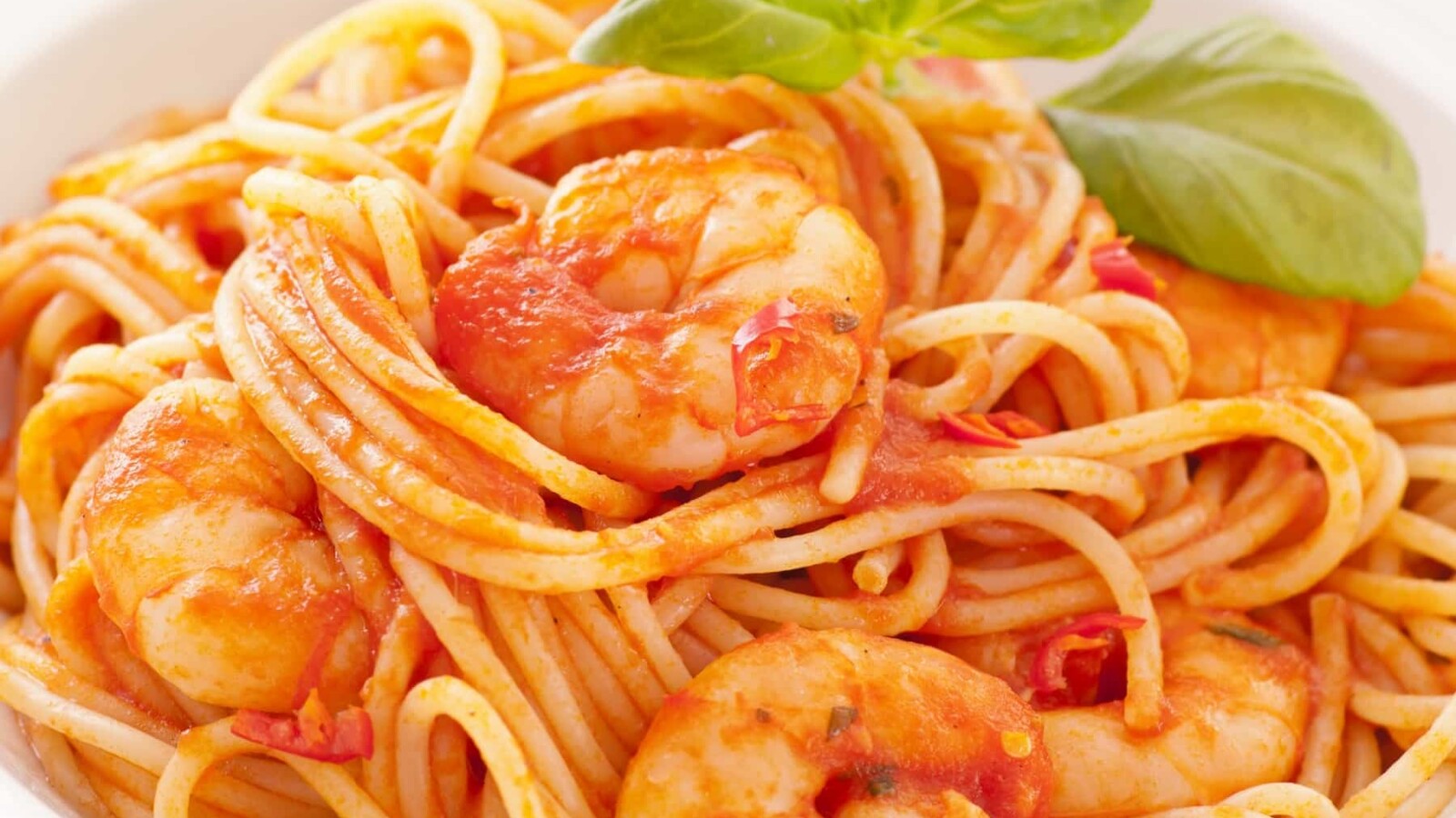 spageti-s-kozicama-u-crvenom-umaku Špageti s kozicama u crvenom umaku, posluženi s listom svježeg bosiljka