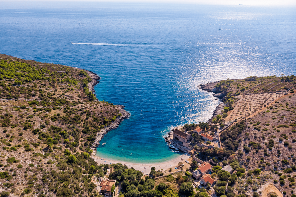 Pogled na uvalu Dubovica na Hvaru s kamenitom plažom i prepoznatljivom kućom uz obalu.