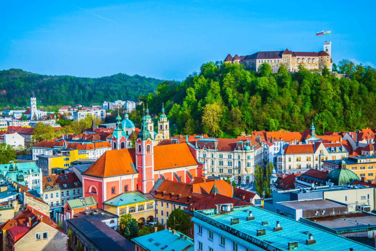 Ljubljanski dvorac na brežuljku s pogledom na staru gradsku jezgru i panoramu Ljubljane, s prepoznatljivim crvenim krovovima i crkvom u središtu, popularna turistička atrakcija glavnog grada Slovenije.