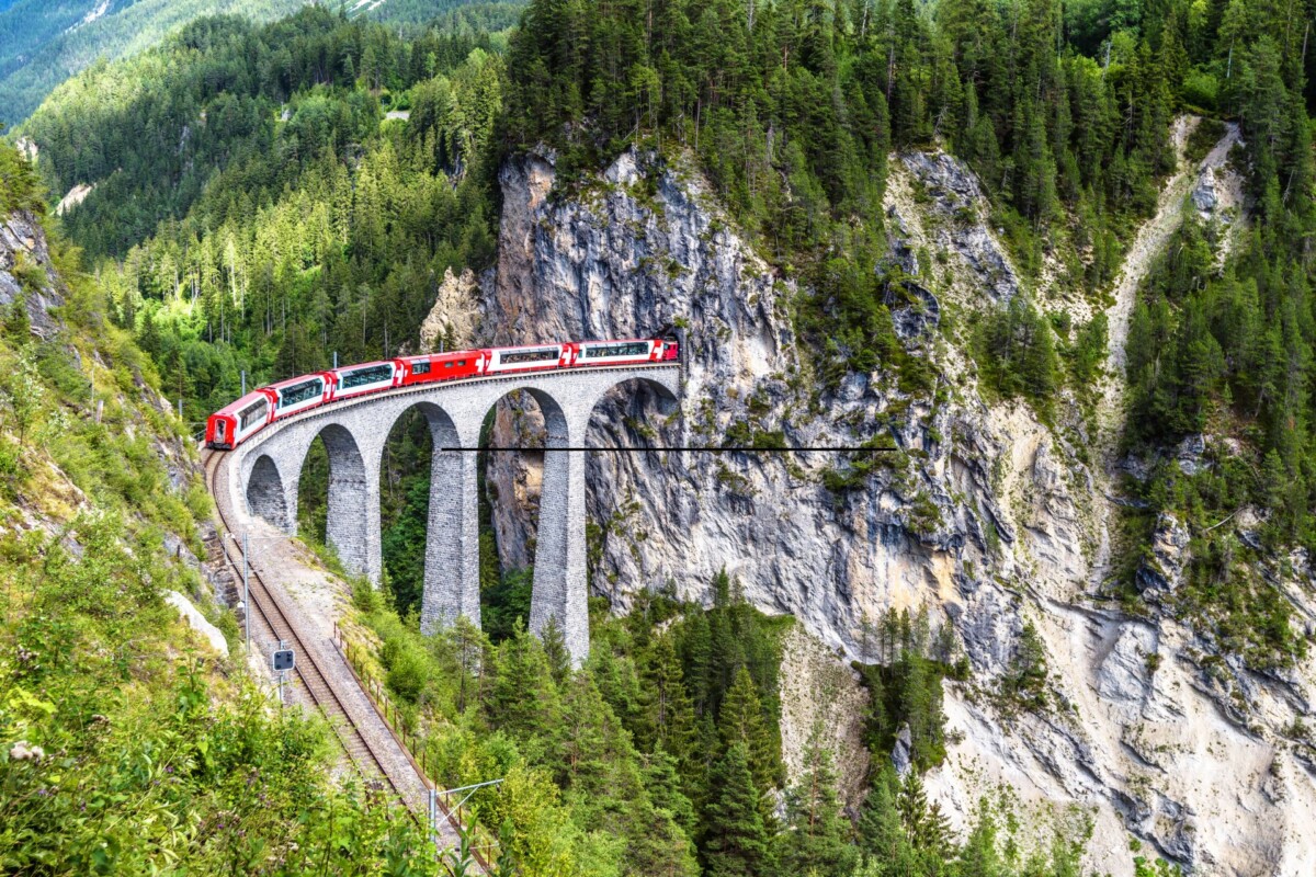 Glacier Express, najsporiji ekspresni vlak na svijetu, prelazi spektakularni kameni vijadukt u švicarskim Alpama. Crveni vlak vijuga kroz strme planinske pejzaže, nudeći putnicima nezaboravan pogled na netaknutu prirodu i impresivne inženjerske građevine.