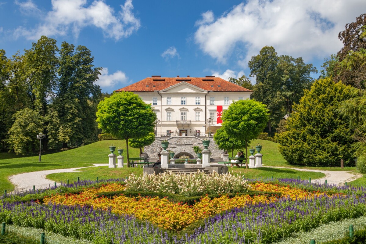Park Tivoli u Ljubljani s raskošnim cvjetnjakom, uređenim stazama i povijesnom vilom u pozadini, popularna atrakcija i najveći park u glavnom gradu Slovenije.