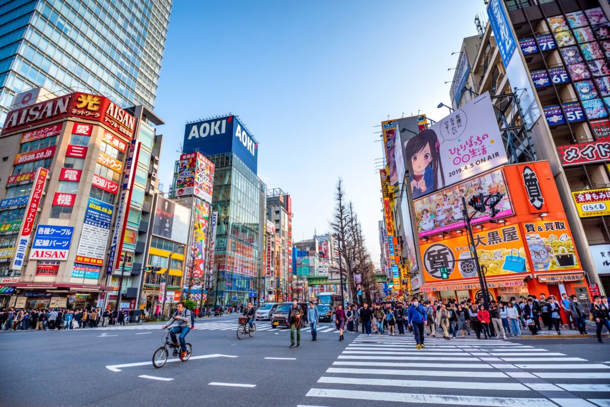 tokio-ulice Prometna gradska ulica u Tokiju, Japan, s mnoštvom ljudi i biciklista, okružena šarenim neboderima i reklamnim panoima.
