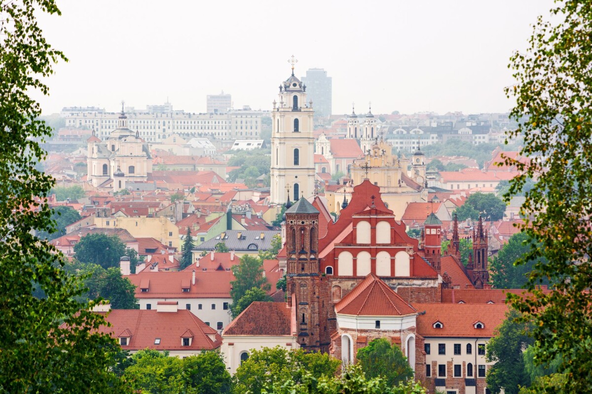 Pogled na staru jezgru Vilniusa s crkvama i crvenim krovovima u zelenom okruženju. Glavni gradovi baltičkih država imaju sve za putovanje, krenite istražiti Vilnius.