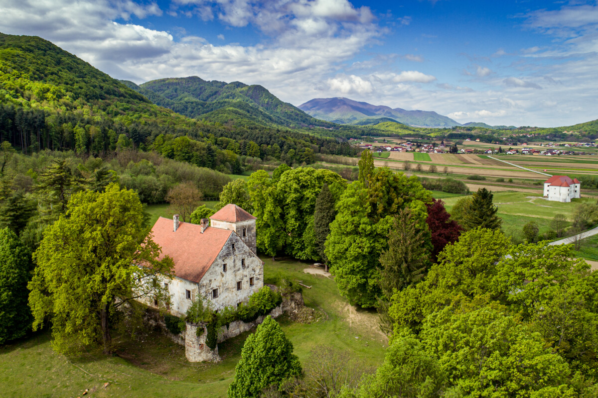 Zeleni krajolik s dvorcima Bela i Bela II u blizini Novog Marofa, Hrvatska. Povijesne znamenitosti smještene među šumovitim brežuljcima, idealne za ljubitelje kulturne baštine i prirode.