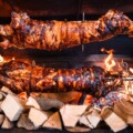 Ražanj s odojkom u vatri, okružen drvom za loženje u restoranu Bistro Europa kod Zagreba