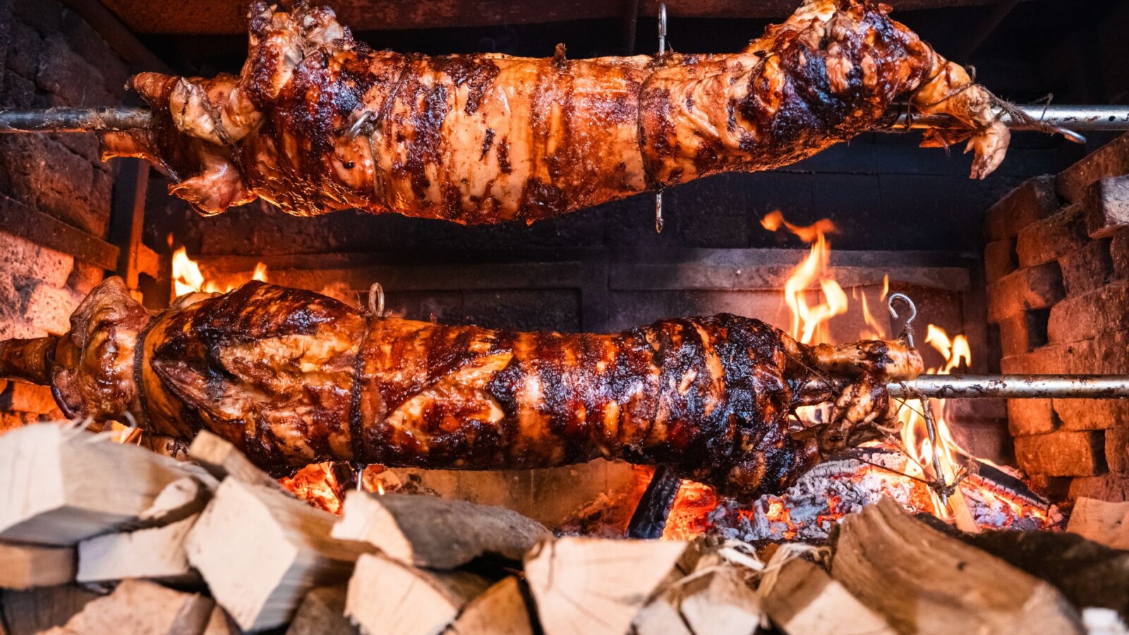 Ražanj s odojkom u vatri, okružen drvom za loženje u restoranu Bistro Europa kod Zagreba
