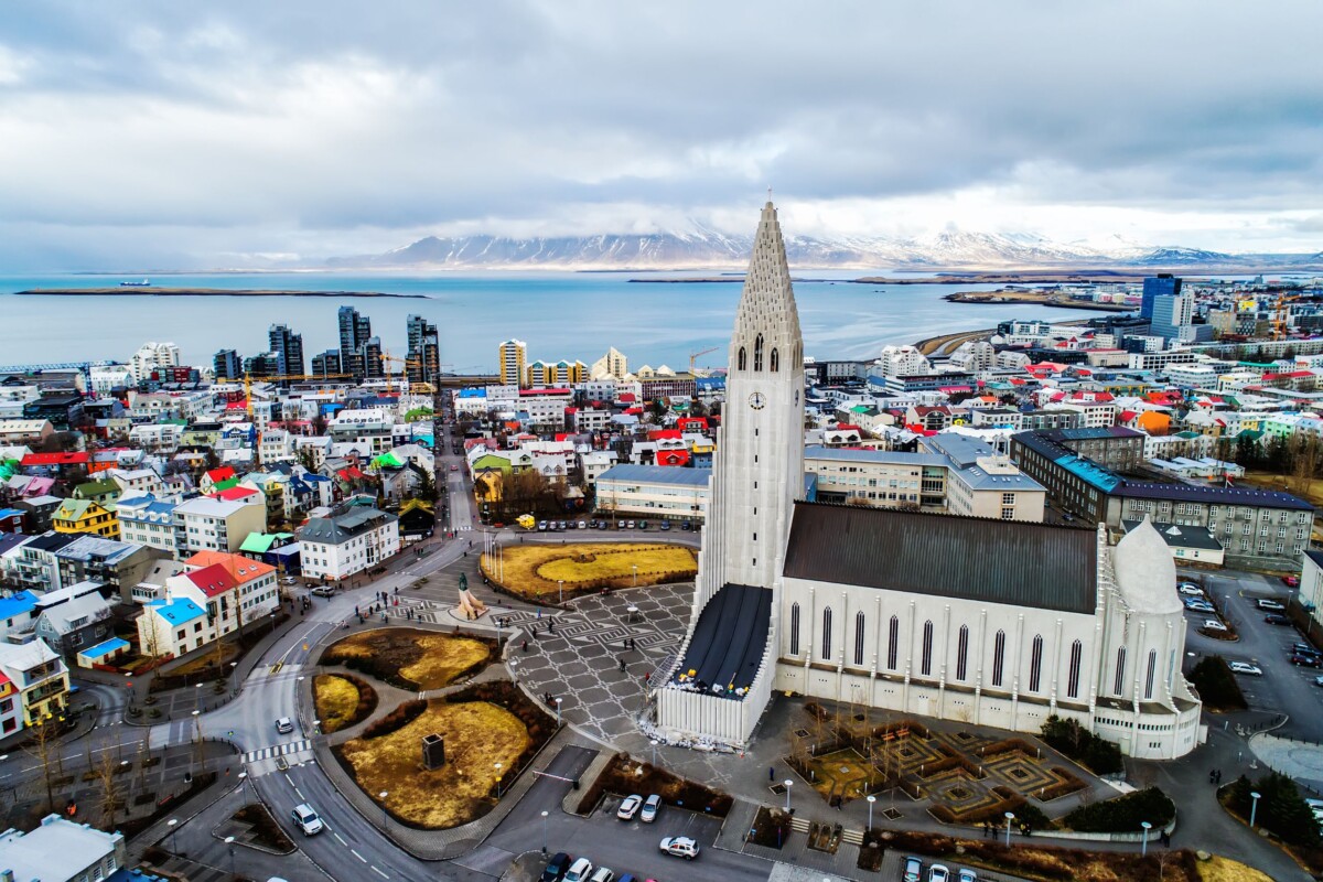 Pogled iz zraka na Reykjavik, slavni glavni grad Islanda, s impozantnom crkvom Hallgrímskirkja u prvom planu i snježnim planinama u pozadini.