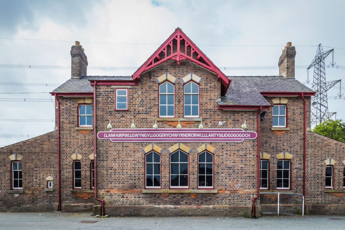 Zgrada željezničke stanice u mjestu Llanfairpwllgwyngyllgogerychwyrndrobwllllantysiliogogogoch u Walesu, poznatom po najdužem nazivu naselja u Europi, s dugim natpisom imena mjesta iznad prozora.