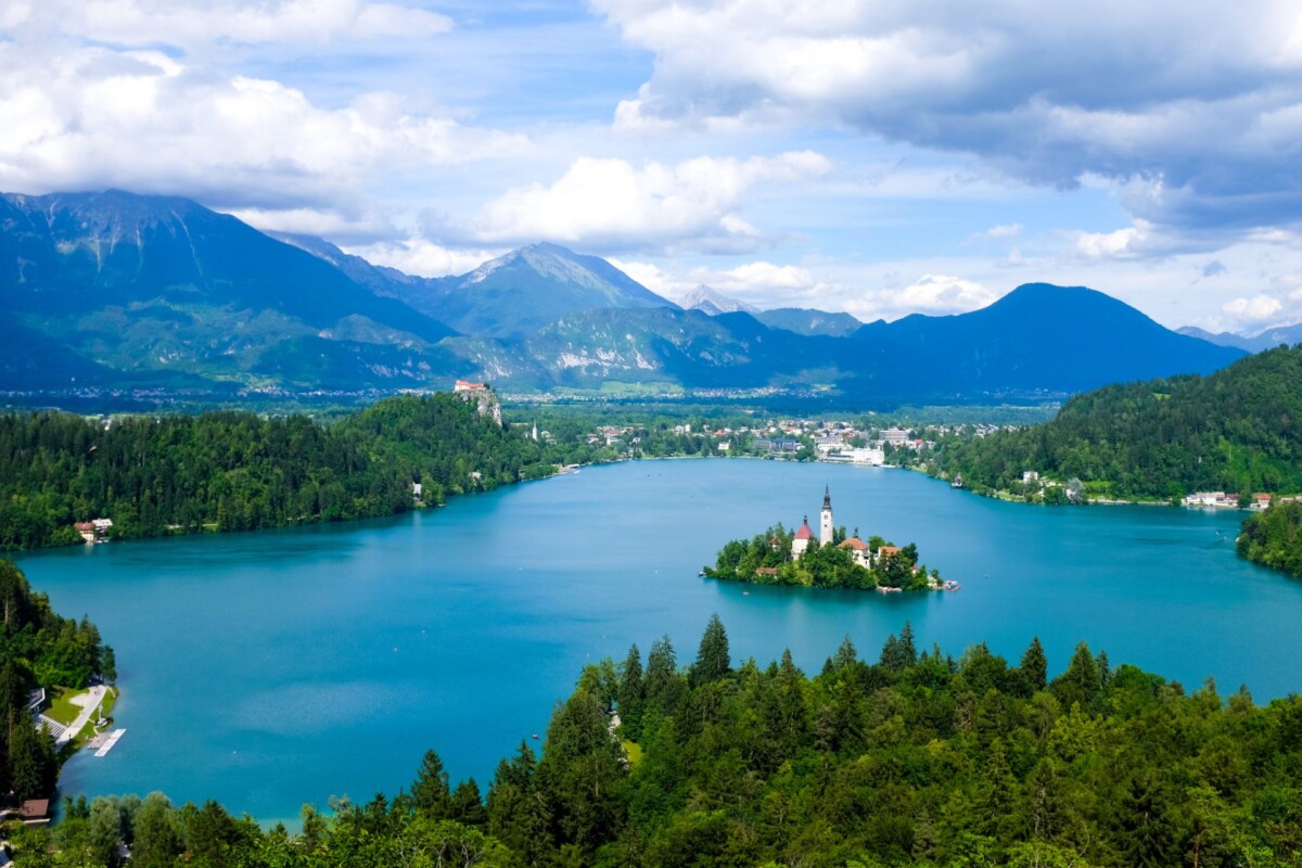 panoramski-pogled-na-bled-izlet Panoramski pogled na Bledsko jezero i crkvicu na otočiću, okružene planinama i bujnom prirodom – jedno od najljepših turističkih odredišta u Sloveniji.