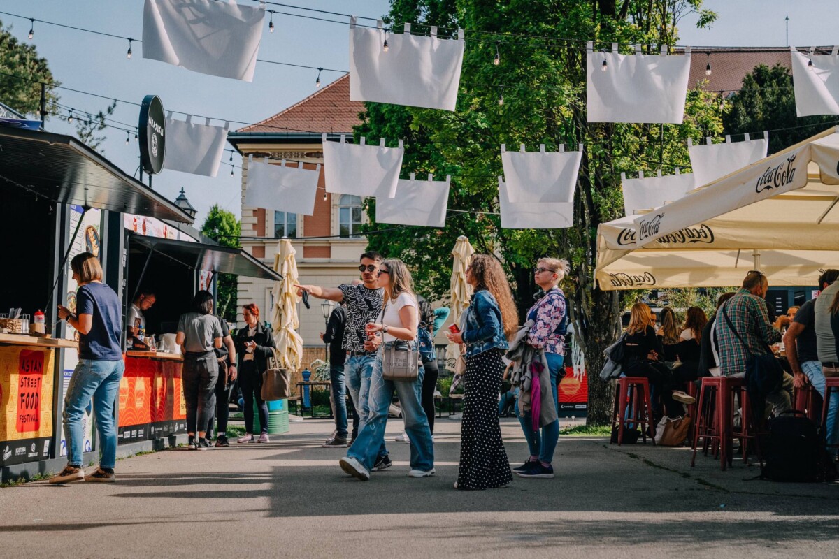 Posjetitelji uživaju u jelima na Asian Street Food Festivalu na Trgu Josipa Jurja Strossmayera u Zagrebu, okruženi kućicama s hranom i dekoracijama na otvorenom.