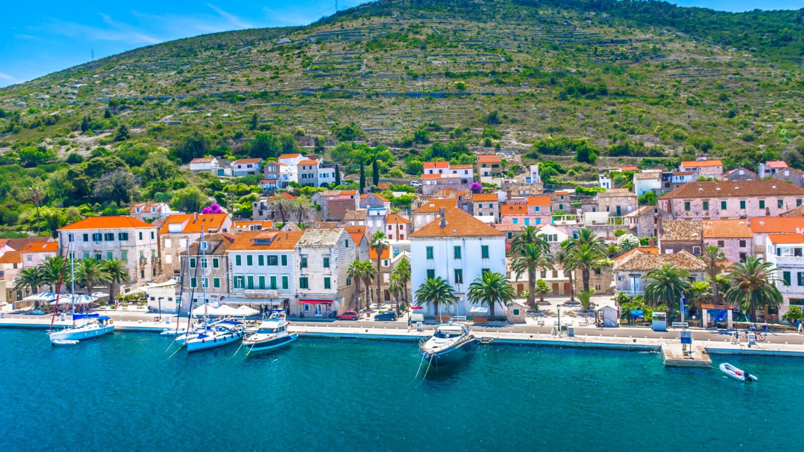 grad-vis-otok-vis Pogled na grad Vis na otoku Visu – slikovita obala s tradicionalnim kamenim kućama, palmama i usidrenim jahtama uz tirkizno Jadransko more