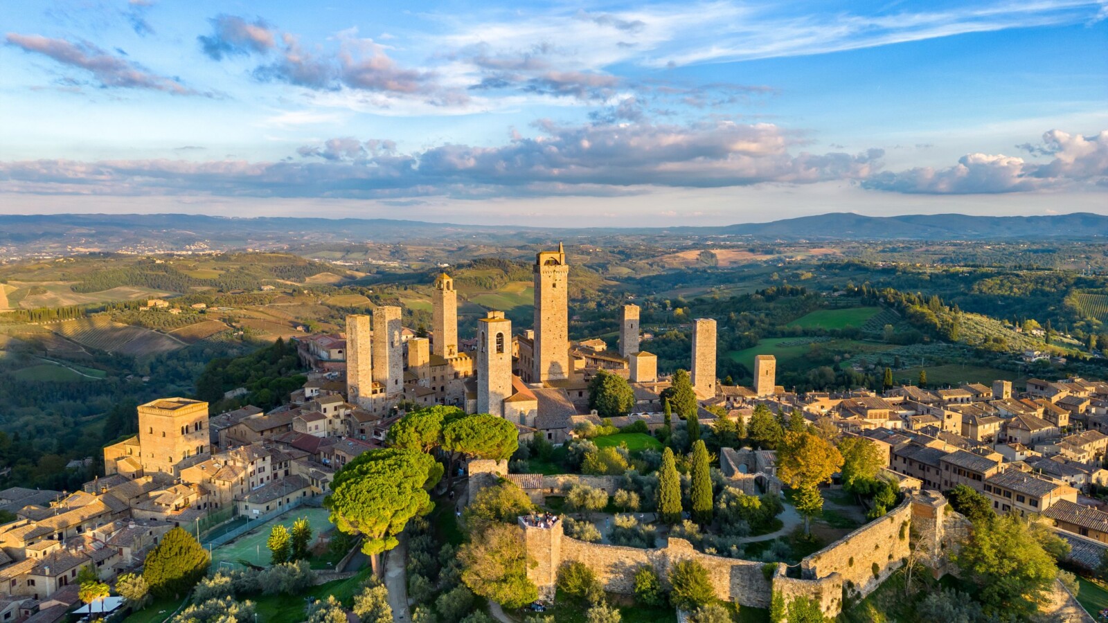san-gimignano-grad-u-toskani Panoramski pogled iz zraka na San Gimignano, srednjovjekovni gradić okružen zelenim brežuljcima Toskane