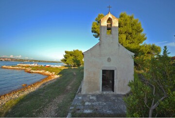 Crkvica sv. Andrije na otoku Babcu, smještena tik uz more i okružena borovima