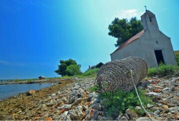 Kamenita crkva sv. Andrije iz 13. stoljeća na mirnoj obali otoka Babca.