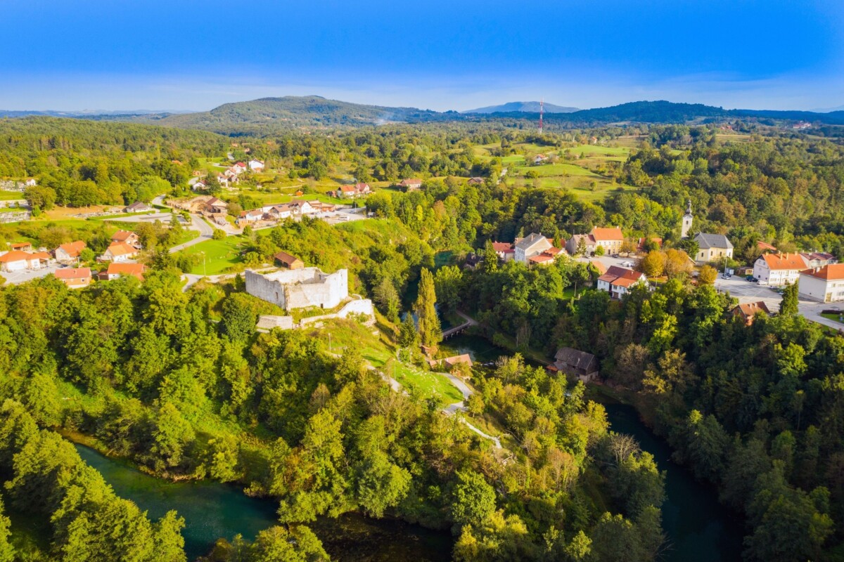 grad-slunj-pogled-iz-zraka Iz zraka snimljen povijesni centar Slunja sa zelenilom, rijekama i tradicionalnim kućama. Izlet u Slunj je uvijek dobra ideja, a posebno će vas oduševiti starinska arhitektura.
