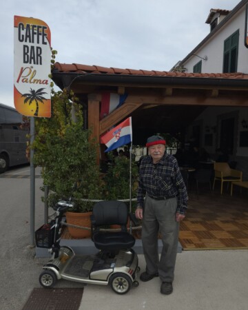 Čovjek sa zastavom ispred caffe bara Palma u mjestu Zablaće
