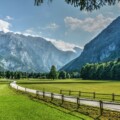 logarska-dolina Pogled na idiličnu Logarsku dolinu u Sloveniji s planinskim vrhovima u pozadini, zelenom livadom i šetnicom uz drvenu ogradu