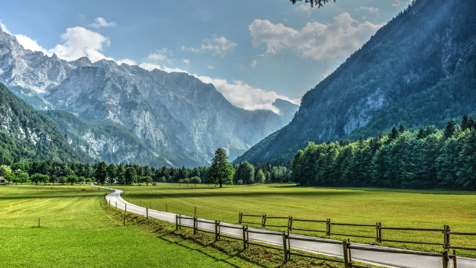 logarska-dolina Pogled na idiličnu Logarsku dolinu u Sloveniji s planinskim vrhovima u pozadini, zelenom livadom i šetnicom uz drvenu ogradu
