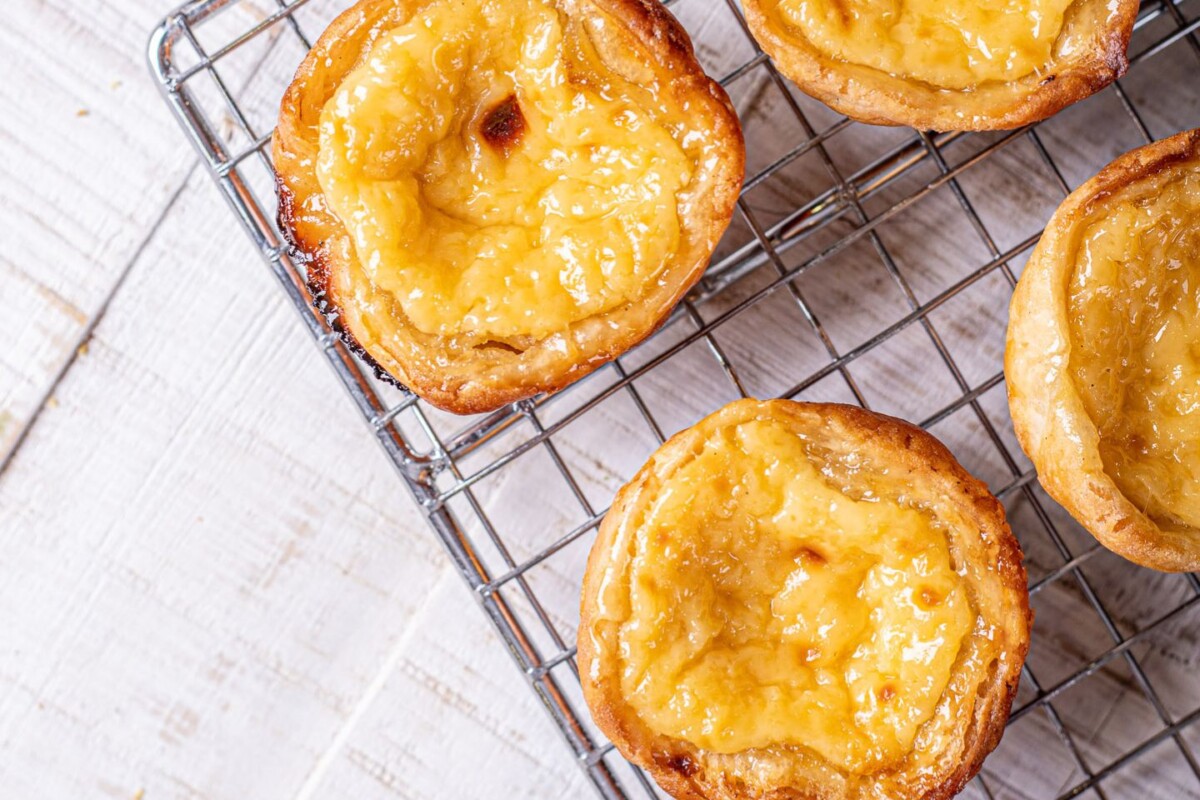 pastel-de-nata-2 Svježe pečeni Pastel de Nata (Pasteis de nata) ohlađeni na rešetki – autentična portugalska slastica prema tradicionalnom receptu za Pastel de Nata, s hrskavom koricom i kremastom sredinom.