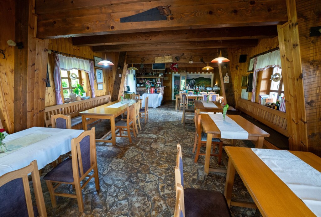 Rustikalni interijer restorana Karlo na Plešivici s drvenim zidovima, kamenim podom i stolovima s bijelim stolnjacima u toploj, domaćoj atmosferi.