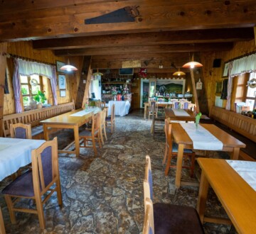 Rustikalni interijer restorana Karlo na Plešivici s drvenim zidovima, kamenim podom i stolovima s bijelim stolnjacima u toploj, domaćoj atmosferi.