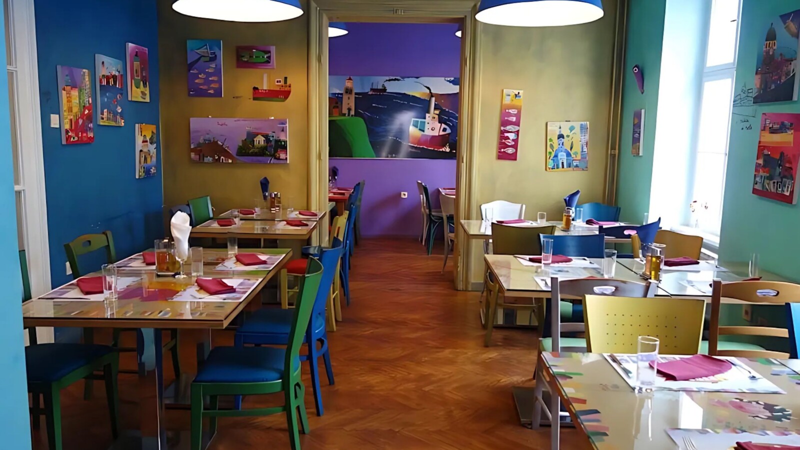 ribica-i-tri-tockice-restoran Interijer restorana Ribica i tri točkice s veselim, šarenim zidovima, ilustracijama i raznobojnim stolicama u toploj, opuštenoj atmosferi.