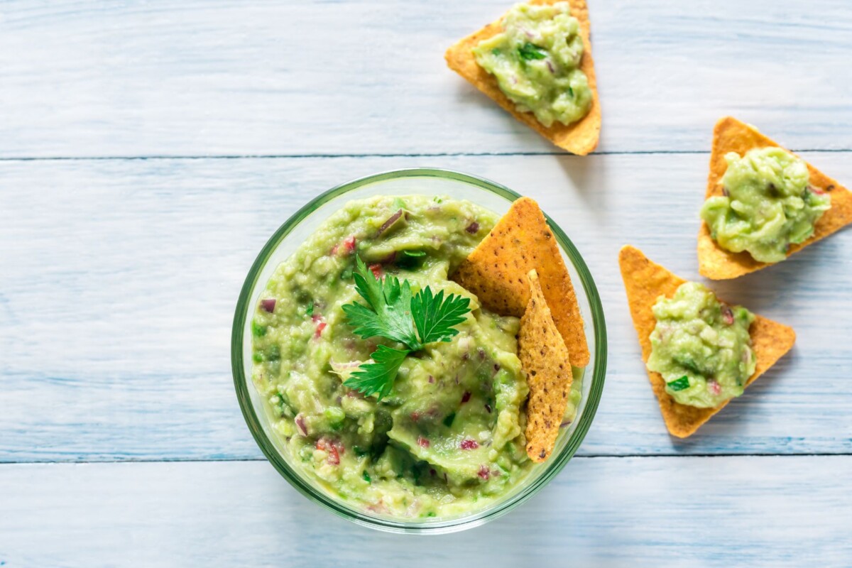 Zeleni namaz guacamole u posudi i na tortilja krekerima