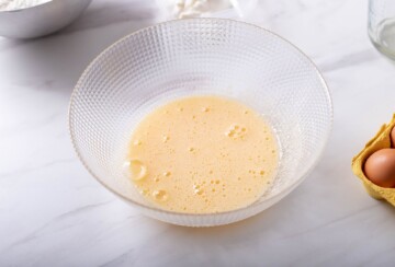 Miksana smjesa od jaja, šećera i vanilin šećera u staklenoj zdjeli.