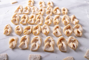 Oblikovane sirove kroštule poredane na površinu, spremne za prženje.