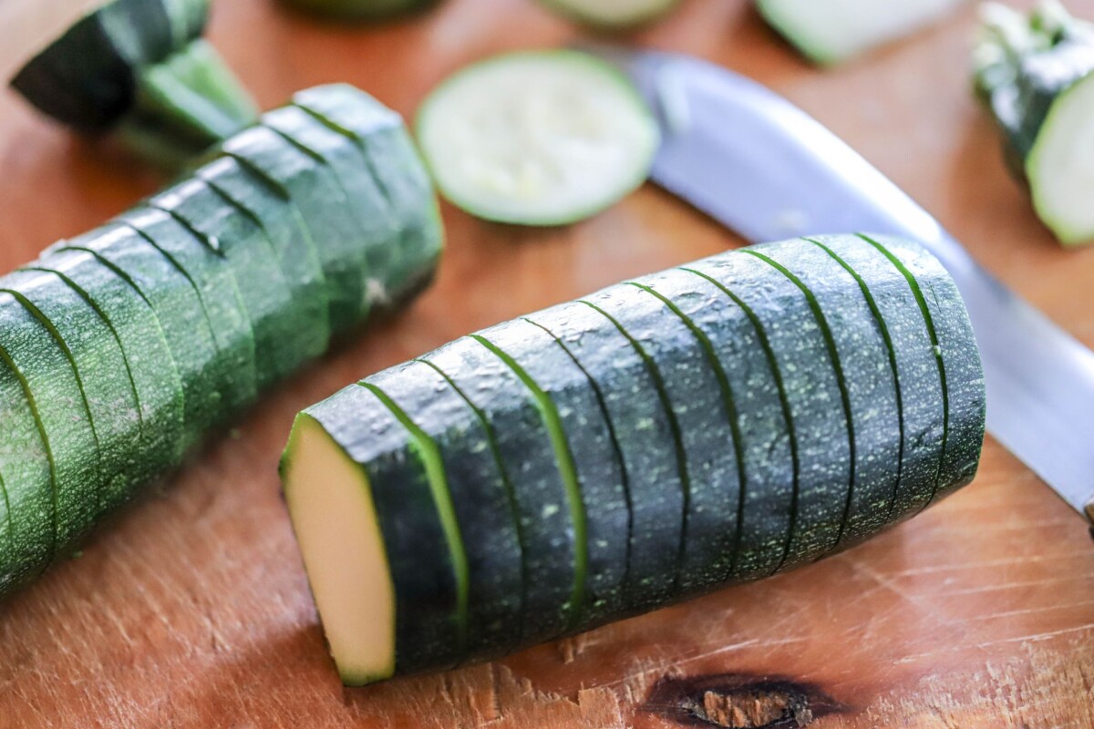 Tikvica narezana po širini u stilu Hasselback, pripremljena za punjenje, na drvenoj dasci uz nož.