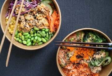 poke bowl dvije smeđe zdjelice pune šarenog povrća na tamnom stolu