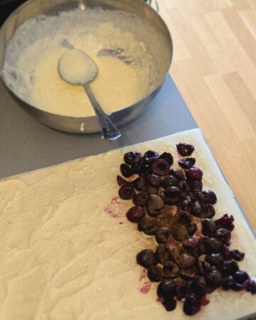 Dodavanje trešanja na treću premazanu koru, prije motanja u štrudlu.