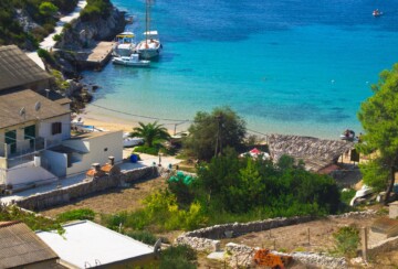 pješčana plaža Porat na Biševu, tirkizno more i mala kuća u uvali