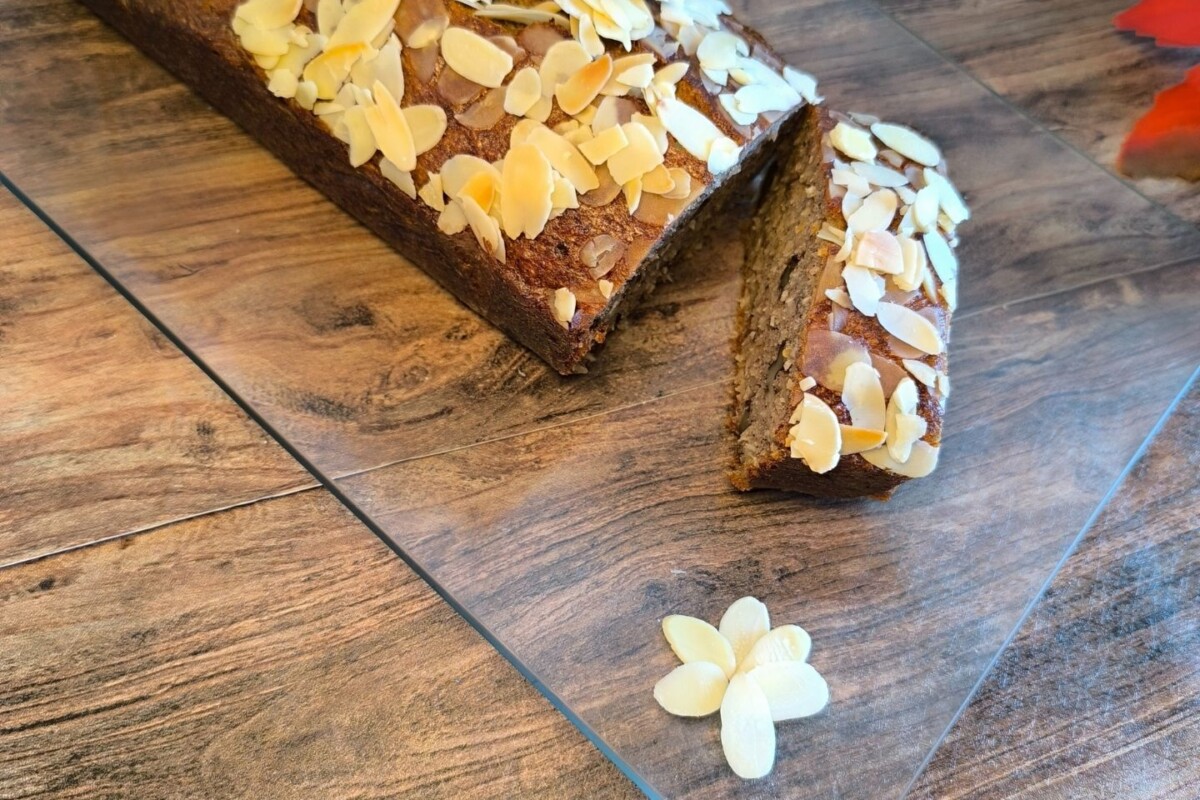 banana-bread-desert Pečeni banana bread s bademima, narezan na šnite, serviran na stolu.