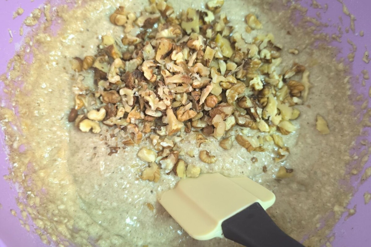 banana-bread-priprema Miješanje smjese za banana bread s dodanim sjeckanim orasima u zdjeli.