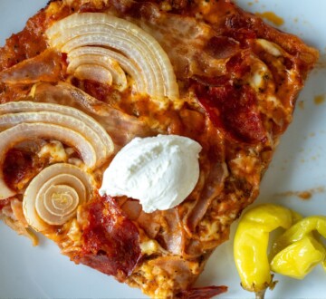 Komad bezglutenske pizze poslužen s kiselim vrhnjem i papričicom