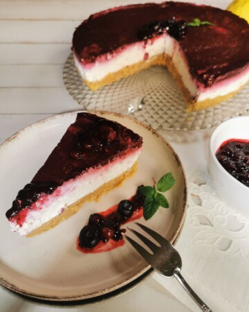 Narezani komadi cheesecakea s preljevom od bobičastog voća posluženi na tanjuru.