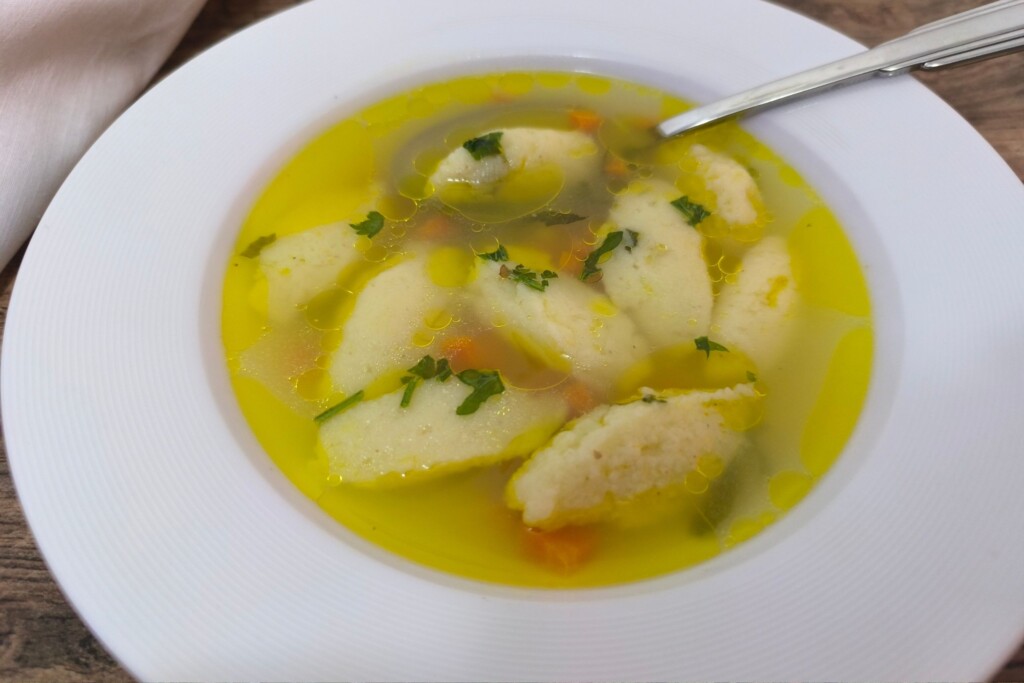 Pileća juha s griz noklicama u dubokom tanjuru, ukrašena sitno sjeckanim peršinom. Domaća pileća juha s noklicama – recept koji spaja jednostavne sastojke u savršenu juhu za svaku priliku, od ručka do svečane večere.