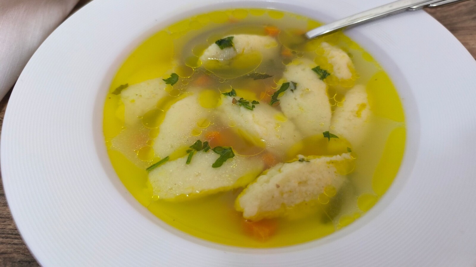 Pileća juha s griz noklicama u dubokom tanjuru, ukrašena sitno sjeckanim peršinom. Domaća pileća juha s noklicama – recept koji spaja jednostavne sastojke u savršenu juhu za svaku priliku, od ručka do svečane večere.