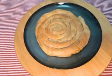 Pečena pita od krumpira u obliku puža na crnom tanjuru