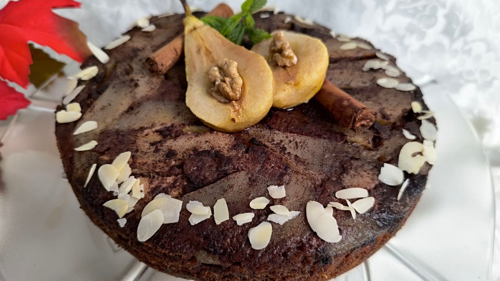 Čokoladna torta s karameliziranim kruškama, dekorirana polovinom kruške i orasima