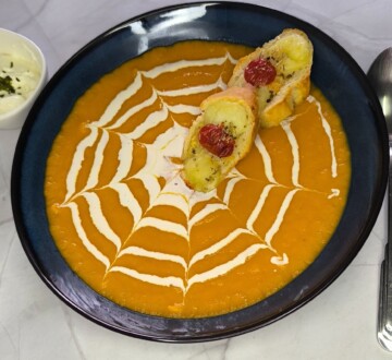 Dekorativno servirana krem juha od batata s kremastim uzorkom i pečenim batatom na vrhu, spremna za uživanje.