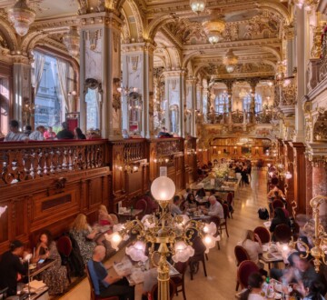 Raskošni interijer New York Caféa u Budimpešti s pozlaćenim stupovima, lusterima i gostima za stolovima