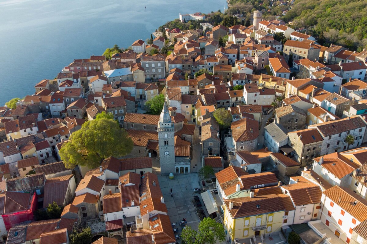 Pogled iz zraka na krovove u Omišlju, s morem u pozadini