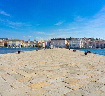 Pogled na mol Audace u Trstu, more i povijesne zgrade u pozadini