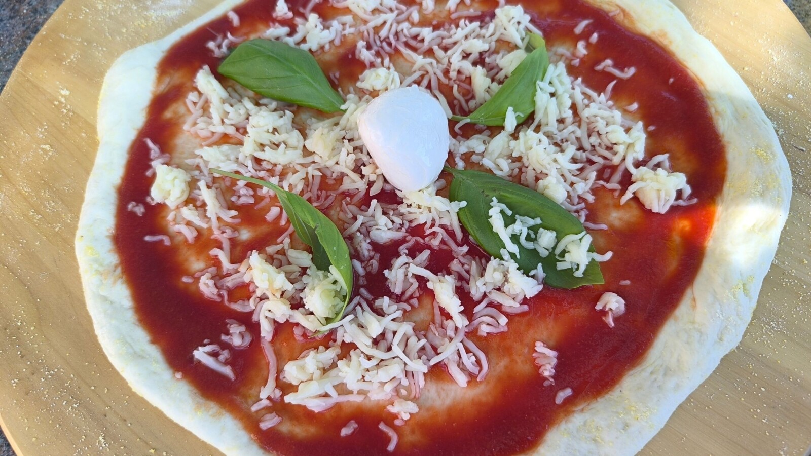 Pizza s umakom od rajčice, sirom i svježim bosiljkom prije pečenja