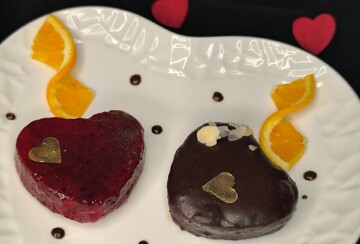Muffini u obliku srca preliveni čokoladom i voćnom glazurom, posluženi uz kriške svježe naranče.